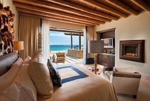 Ein Hotelzimmer mit einem großen Bett, einer Couch, einem Fernseher und Meerblick.