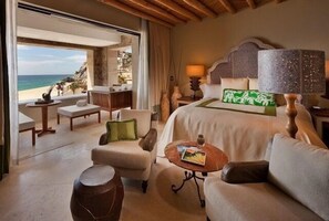 Ein Hotelzimmer mit Bett, Sofa, Couchtisch und Blick auf den Strand.