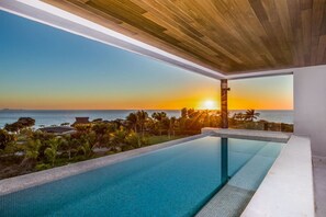 Ein moderner Infinity-Pool mit Blick auf den Sonnenuntergang über dem Meer.