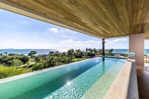 Piscina com vista para o oceano e paisagem tropical.