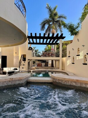 Uma área de piscina com cachoeira, assentos e vista para uma palmeira.