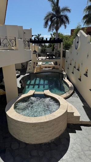 Ein Poolbereich mit Whirlpool, Liegestühlen und einer Pergola.