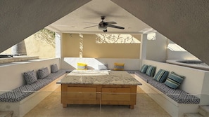 A sunlit interior with a central seating area, a ceiling fan, and a view through a triangular opening. - Grand Villa Famlee - multi-family rental sleeps 16 (Cabo San Lucas)