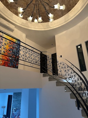 A staircase with ornate black railings, a stone ceiling, and a colorful abstract painting on the wall. - Grand Villa Famlee - multi-family rental sleeps 16 (Cabo San Lucas)