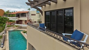 A poolside area with a view of a building, a pergola, and a chair. - Marbella lane-Scenic Home with Amazing OceanViews (Cabo San Lucas)