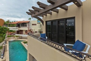 Ein Poolbereich mit Blick auf ein Gebäude, eine Pergola und einen Stuhl.
