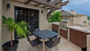 An outdoor kitchen area with a grill, dining table, and chairs. - Marbella lane-Scenic Home with Amazing OceanViews (Cabo San Lucas)