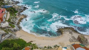 A coastal view with a beach, rocky shoreline, and buildings. - Marbella lane-Scenic Home with Amazing OceanViews (Cabo San Lucas)