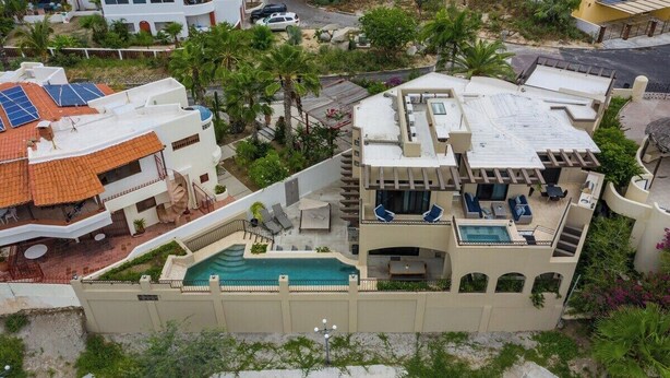 Ein Wohnhaus mit Swimmingpool, Sitzgelegenheit im Freien und Solaranlage.