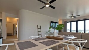 Ein stilvoller Essbereich mit Tisch, Stühlen und Deckenventilatoren.