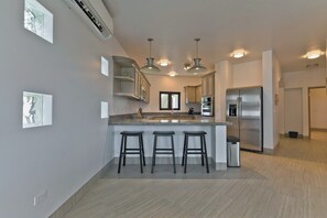 A modern kitchen with a central island, bar stools, pendant lighting, and stainless steel appliances. - Marbella lane - Stylish Private Villa OceanViews (Cabo San Lucas)