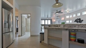 Eine moderne Küche mit Marmorarbeitsplatte, Edelstahlgeräten und Deckenventilator.