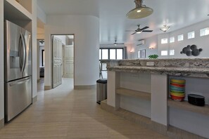 A modern kitchen with a marble countertop, stainless steel appliances, and a ceiling fan. - Marbella lane - Stylish Private Villa OceanViews (Cabo San Lucas)