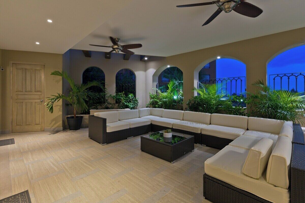 A spacious living area with a sectional sofa, a coffee table, and potted plants.