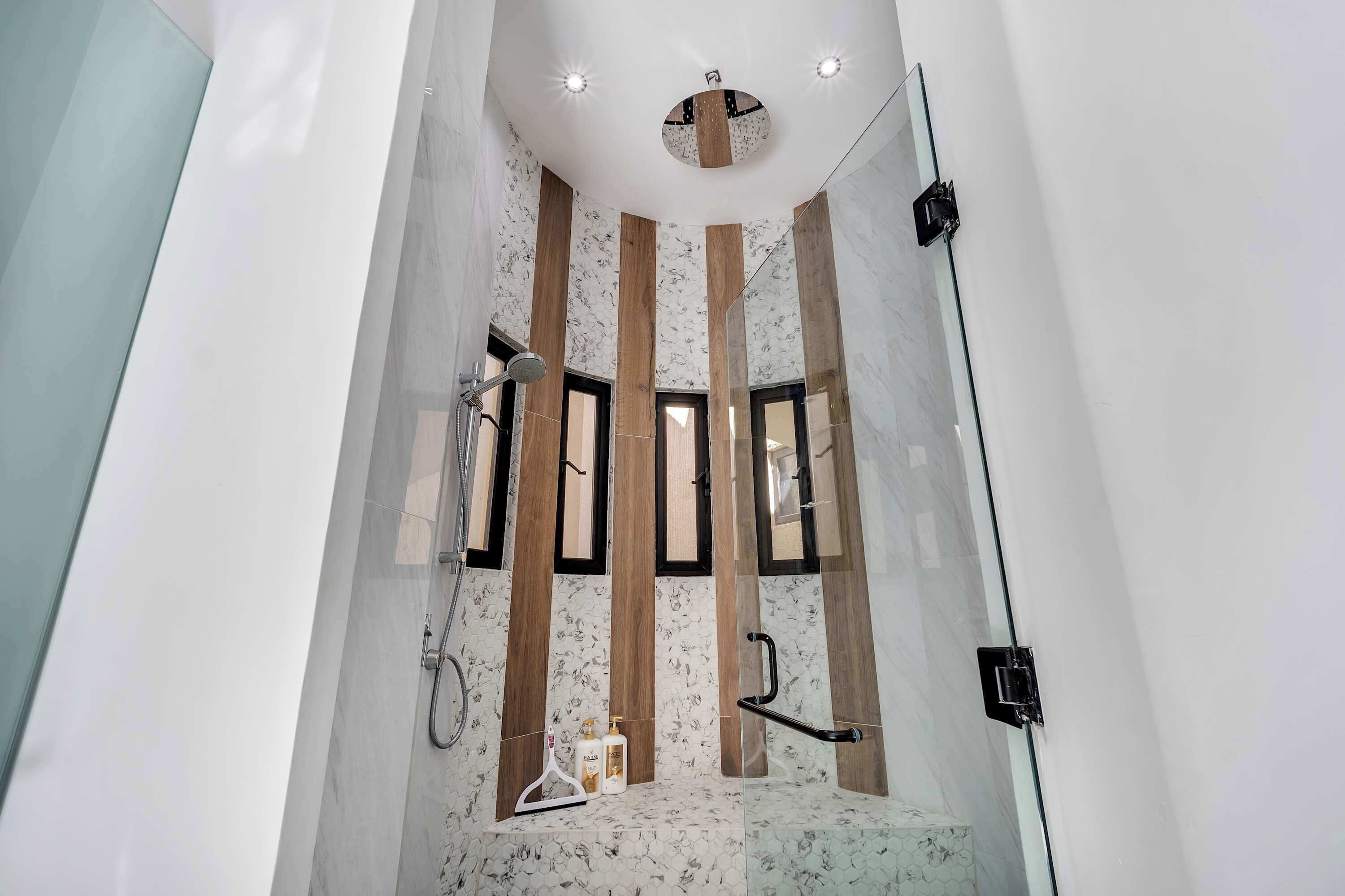 Une salle de bain moderne avec une douche, une porte en verre et un décor mural en panneaux de bois.