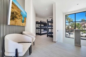 A modern hotel room with bunk beds, a large window with a view of palm trees, and a painting on the wall. - Marbella Lane PrimeVilla n Modern Home Comfort (Cabo San Lucas)