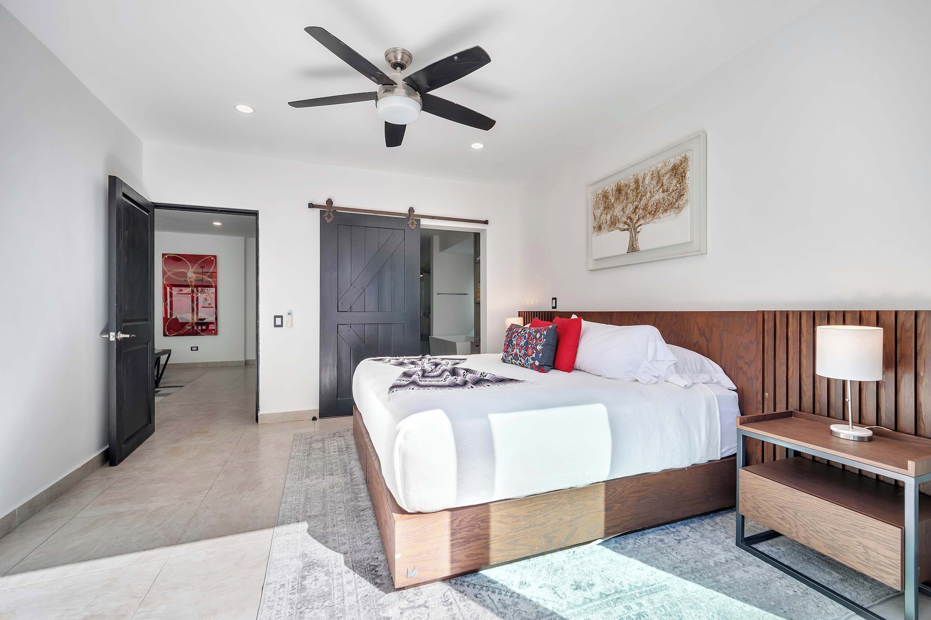 Une chambre à coucher moderne avec un lit, une table de chevet et un ventilateur de plafond.