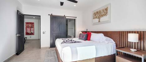 A modern bedroom with a bed, bedside table, and a ceiling fan.