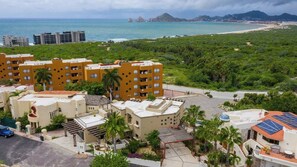 A residential area with multi-story buildings, a parking lot, and a view of the ocean. - Marbella Lane Premium Ocean View Villa & Pool (Cabo San Lucas)