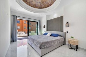 A modern bedroom with a large bed, a small bedside table, and a view of the outside. - Marbella Lane Premium Ocean View Villa & Pool (Cabo San Lucas)