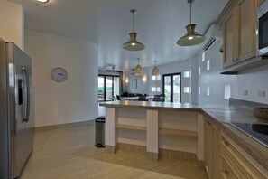 A modern kitchen with a central island, stainless steel appliances, and pendant lighting. - Marbella Lane Coastal Elegance Villa with Pool (Cabo San Lucas)