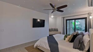 A modern bedroom with a bed, a ceiling fan, a TV, and a window with curtains. - Marbella Lane Coastal Elegance Villa with Pool (Cabo San Lucas)