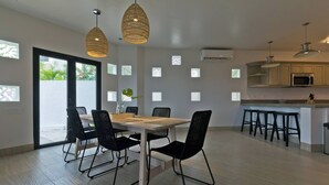 A modern kitchen with a dining area, featuring a large table, black chairs, and pendant lights. - Marbella Lane Coastal Elegance Villa with Pool (Cabo San Lucas)