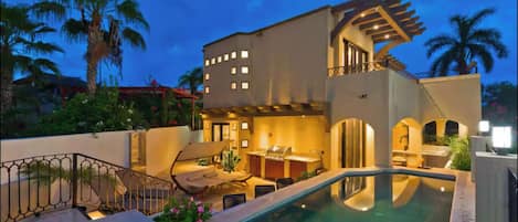 A modern building with a swimming pool, outdoor seating, and a covered patio area.