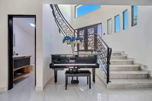 A grand piano in a spacious, well-lit room with a marble staircase and a decorative railing. - Marbella Lane Grand 5BR Oasis Villa Getaway (Cabo San Lucas)