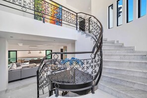 Ein modernes Interieur mit einer Wendeltreppe, einem Wohnbereich mit Sofa und Blick ins Freie.