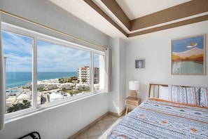 Une chambre d’hôtel dotée d’une grande fenêtre donnant sur la plage et l’océan.