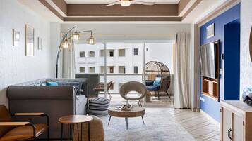 A modern living room with a sofa, chairs, a coffee table, and a balcony with a view of a building.
