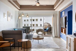 A modern living room with a sofa, chairs, a coffee table, and a balcony with a view of a building. - Oceanview Condo 2BR 2BA at Las Palmas Resort (Puerto Peñasco)