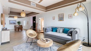 Uma sala de estar moderna com um sofá cinzento, mesa de centro de madeira e ventoinha no teto.