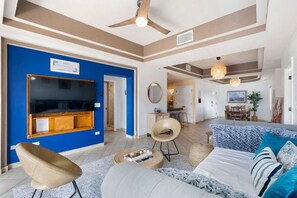 A spacious living room with a large TV, comfortable seating, and a ceiling fan. - Oceanview Condo 2BR 2BA at Las Palmas Resort (Puerto Peñasco)