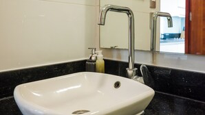 A bathroom with a white sink, a mirror, and a black countertop. - Charming Studio in Las Condes  (Las Condes)