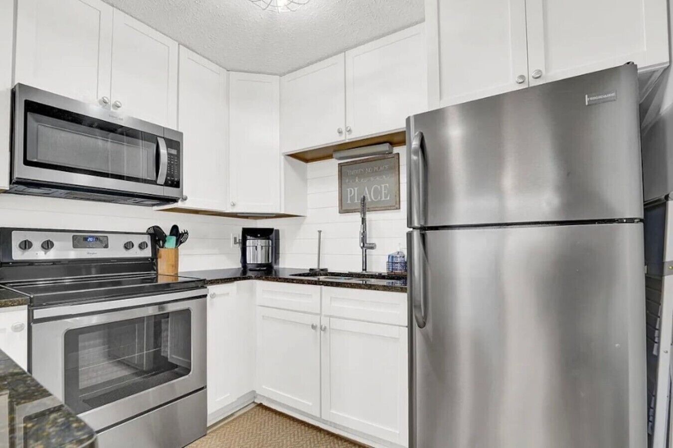 A modern kitchen with white cabinetry, stainless steel appliances, and a built-in microwave.