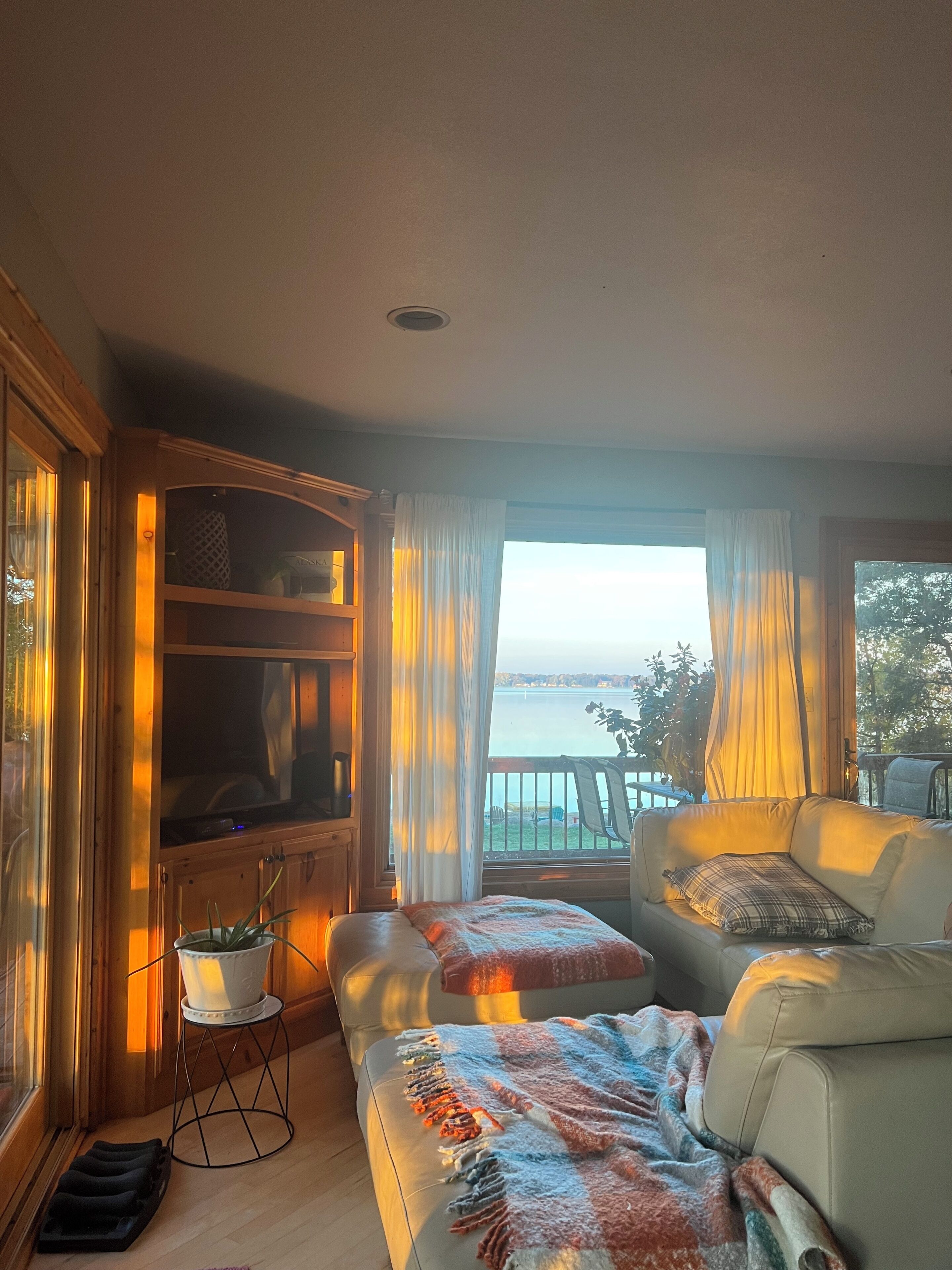 A living room with a sofa, a television, and a view of the sea.