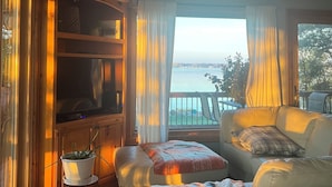 Ein Wohnzimmer mit einer Couch, einem Fernseher und Blick auf das Meer.