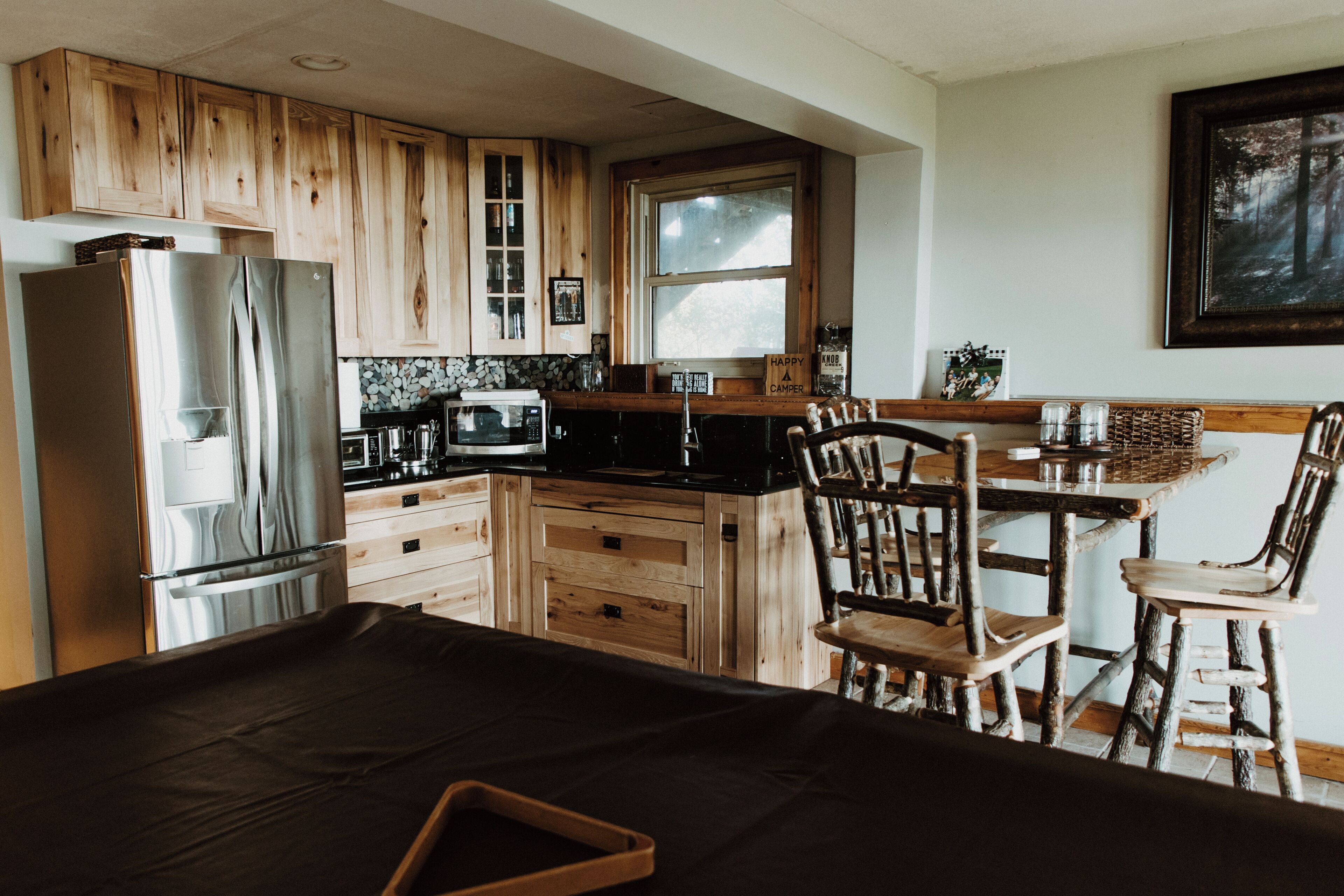A kitchen with wooden cabinets, a refrigerator, a microwave, and a dining area with a table and chairs.