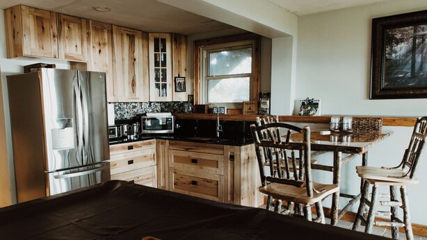 Eine Küche mit Holzausstattung, einem Kühlschrank, einer Mikrowelle und einem Essbereich mit Tisch und Stühlen.