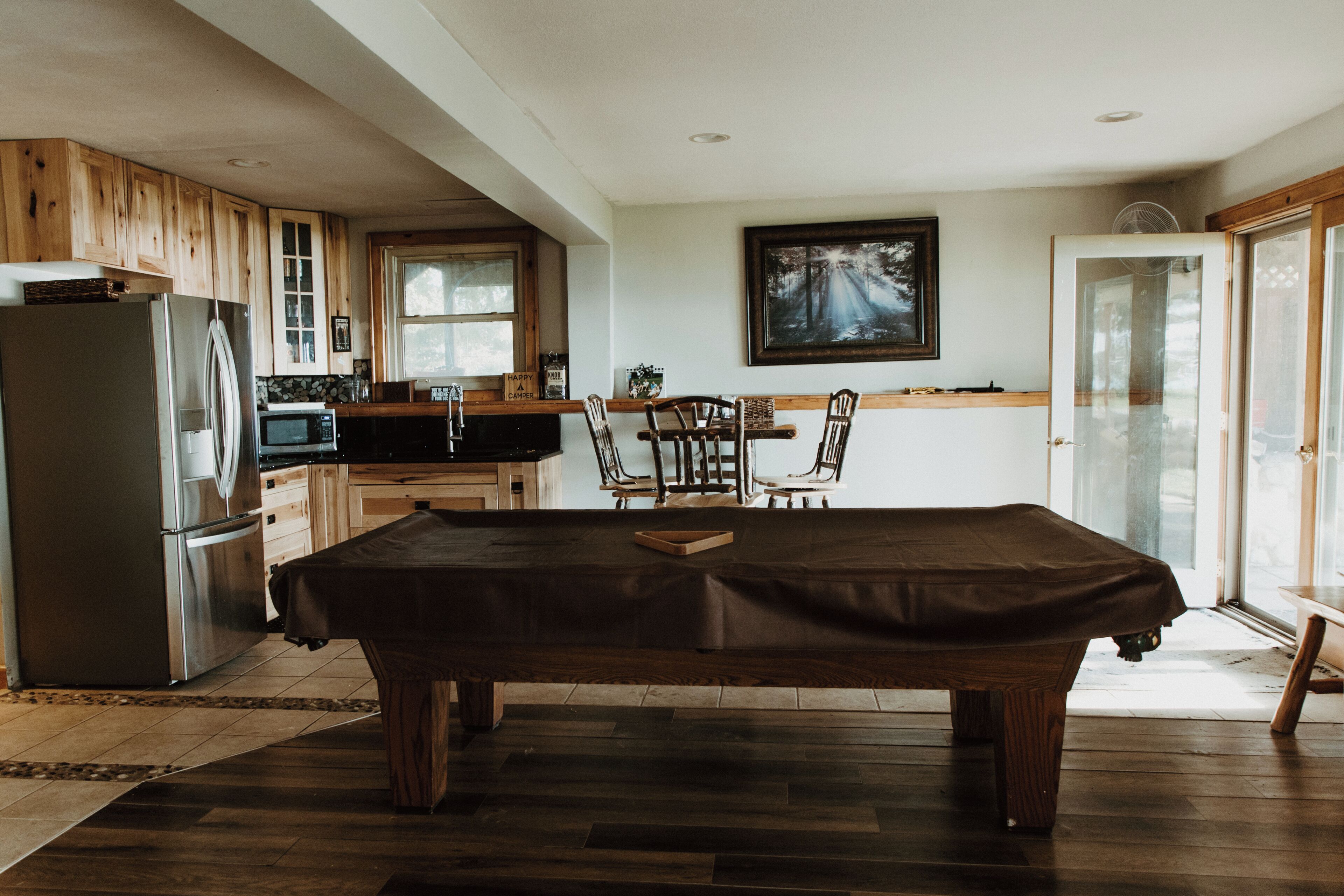 A kitchen with wooden cabinets, a refrigerator, a microwave, and a dining table with chairs.