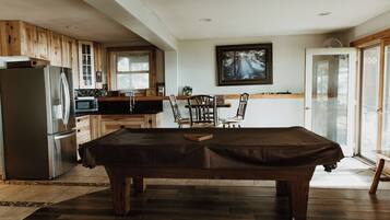 A kitchen with wooden cabinets, a refrigerator, a microwave, and a dining table with chairs.