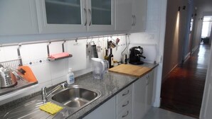Una cucina con un lavello in acciaio inox, un tagliere in legno e diversi utensili da cucina.