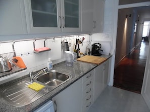 A kitchen with a stainless steel sink, a wooden cutting board, and various kitchen utensils. - Gulbenkian Park Residence Apartment (Lisbon)