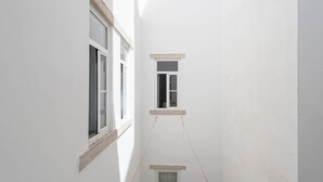 Un corridoio stretto con due finestre, una per lato, e una più piccola in fondo.