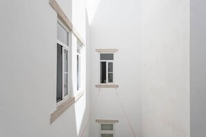A narrow corridor with two windows, one on each side, and a small window at the end. - Gulbenkian Park Residence Apartment (Lisbon)