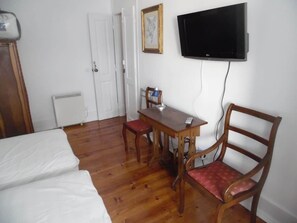 A room with a bed, a wooden table with chairs, a television mounted on the wall, and a radiator. - Gulbenkian Park Residence Apartment (Lisbon)