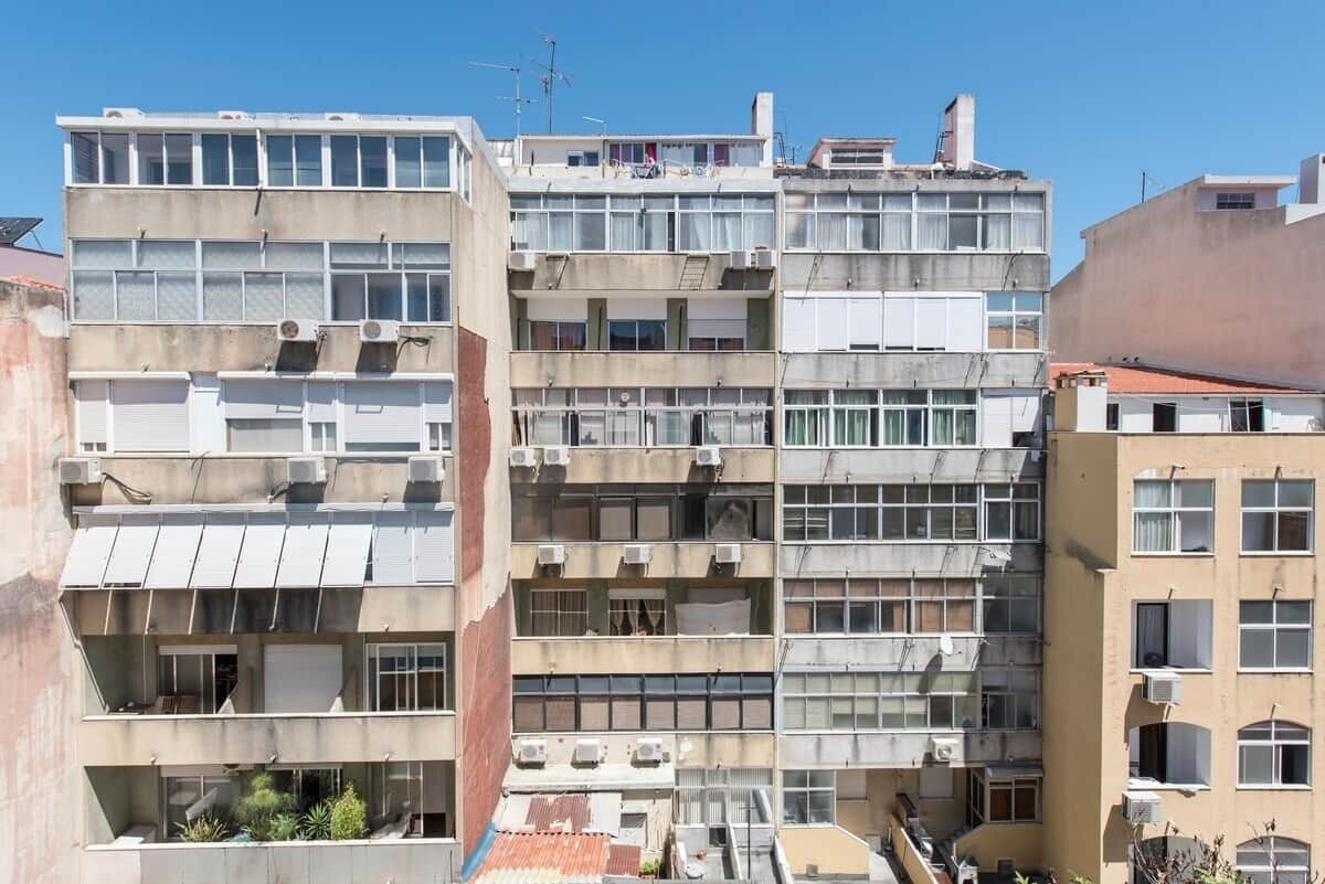 Un immeuble à plusieurs étages doté de balcons, de climatiseurs et d’un toit plat.