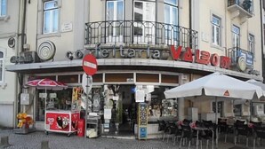 Un negozio con posti a sedere all'aperto, un segnale di divieto di accesso e una macchina distributrice.
